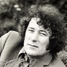 A portrait of Seamus Heaney, with him reclining in a field 