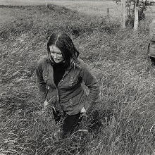 The Heaney family in a field with Marie Heaney walking toward the foreground and others near a fence in the background