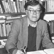 Arthur Terry seated at a desk with bookshelves behind him, a pipe in his right hand